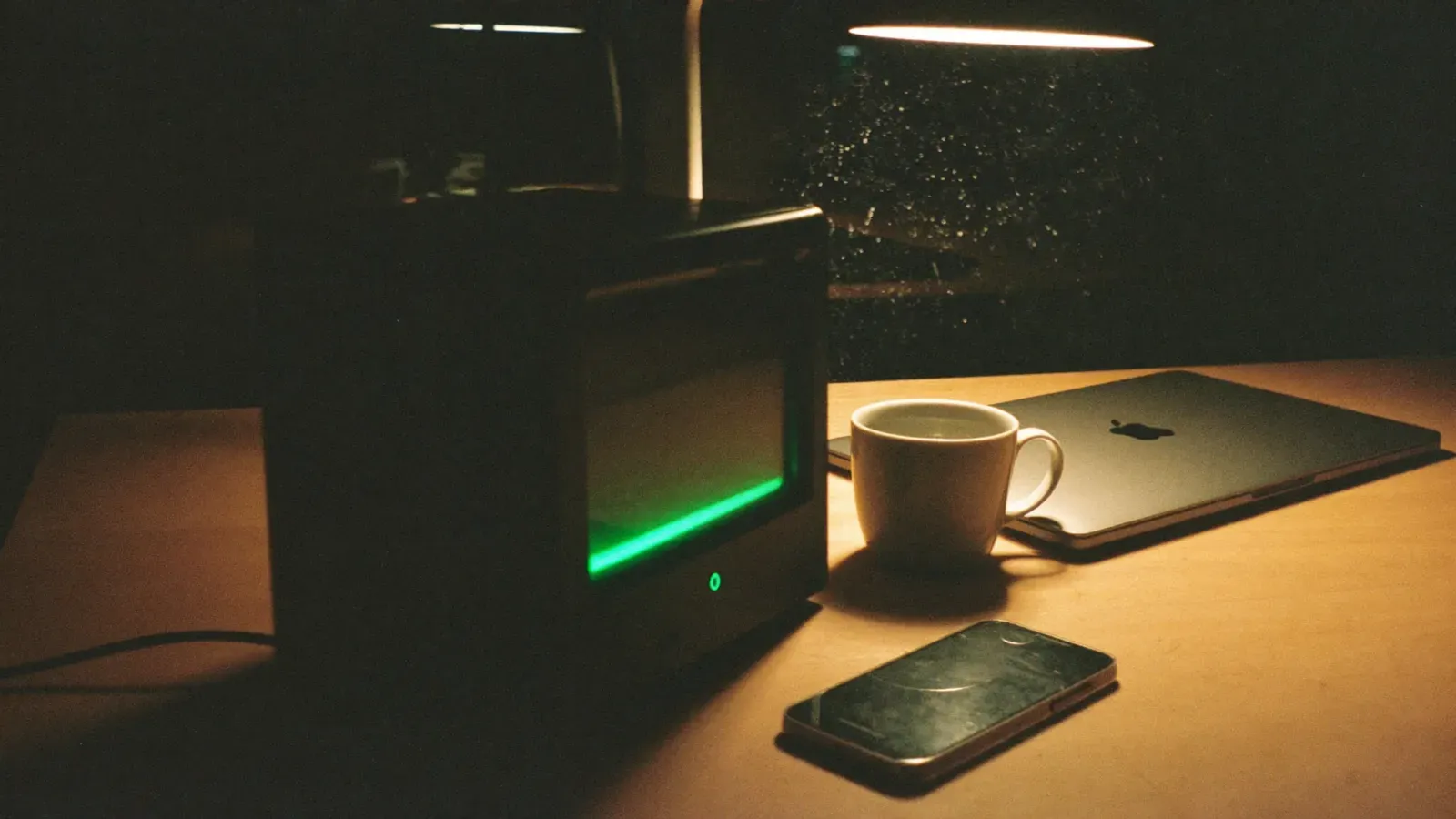 Mini-pc met groen statuslampje op een bureau bij avond
